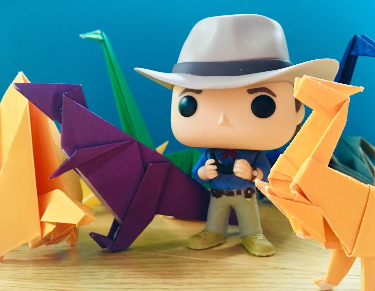 Origami dinosaurs surrounding an Alan Grant figurine from Jurassic Park.
